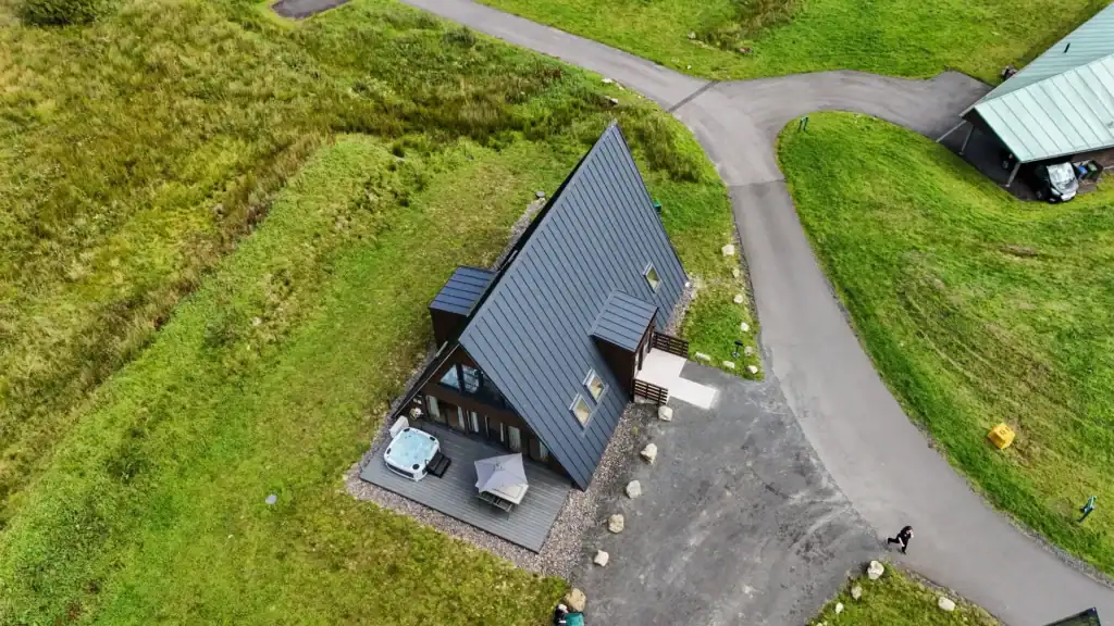 Aerial view of an A-frame lodge with a private hot tub and decking area