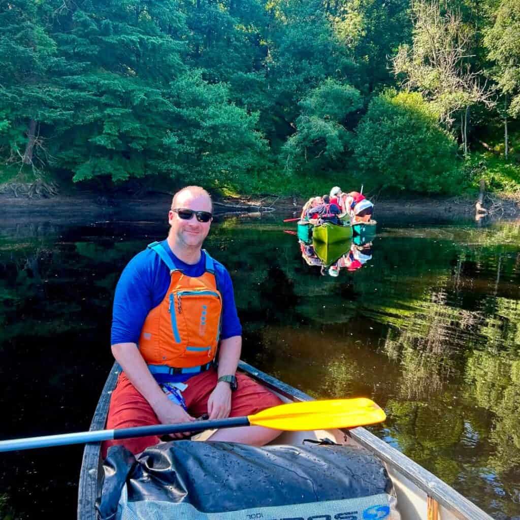 Stephen ‘Pottsy’ Potts from the Respite Care team canoeing on the river, with guests in canoes behind him