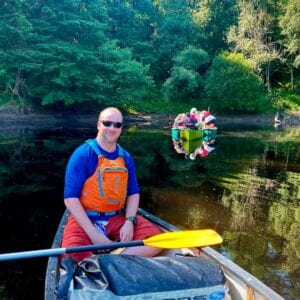 Stephen ‘Pottsy’ Potts from the Respite Care team canoeing on the river, with guests in canoes behind him