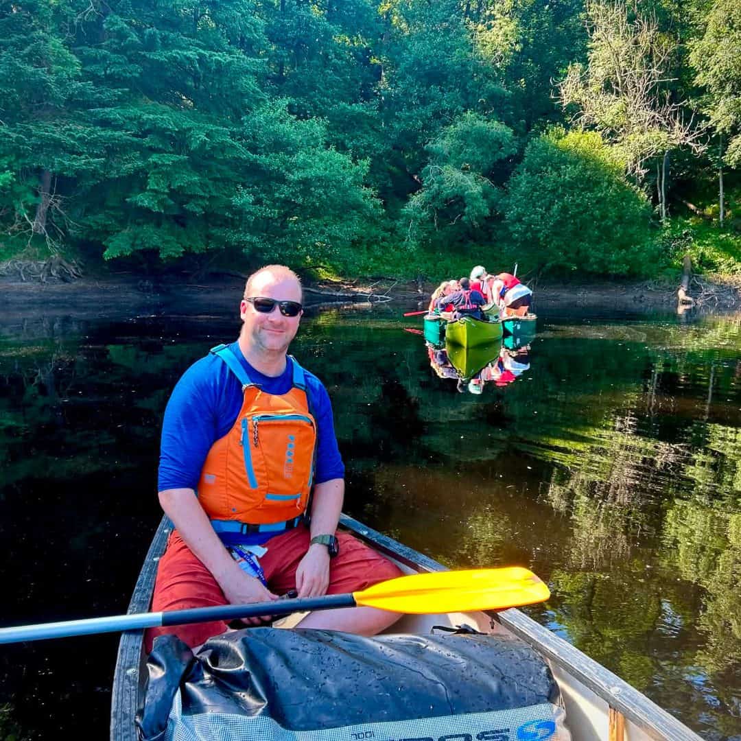 Stephen ‘Pottsy’ Potts from the Respite Care team canoeing on the river, with guests in canoes behind him